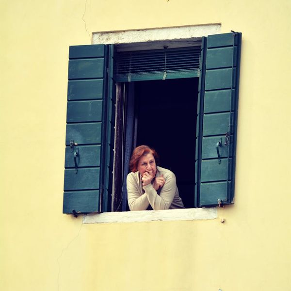 Person looking thoughtfully out a window with a serene and clear expression.