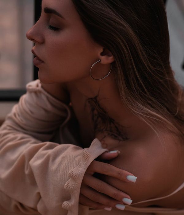 Woman smiling gently with her eyes closed in a calm, dark environment with mint light.